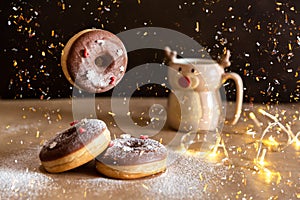 Christmas breakfast table with flying chocolate donut decorated with red and white sprinkles, hot cocoa in deer mug on