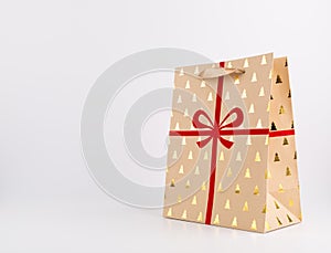 Christmas Brown Paper Bag with Red Ribbon and glittering golden trees on white background, glittering,
