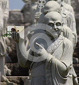 Christmas Buddhist monk statue holding a present with a blank card and pointing at it