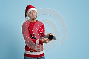 Christmas Budget Concept. Crying Young Man In Santa Hat Showing Empty Wallet