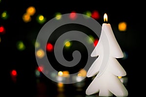 Christmas burning candle on the background of colorful lights garland, bokeh.