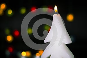 Christmas burning candle on the background of colorful lights garland, bokeh.