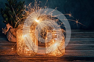 Christmas burning sparklers in a glass jar on wooden table