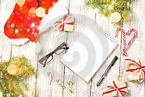Christmas and Business Items with Copy Space cropped Santa Cap Notepad Pen Glasses and decorated Gift Box and fir tree