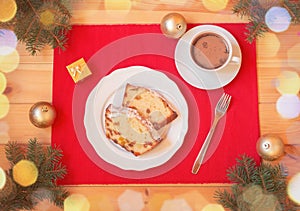 Christmas cake with candied fruits and raison, homemade hot chocolate, christmas balls and fir branches on wooden table. Top view