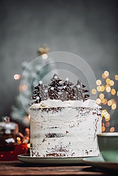 Christmas cake with chocolate Christmas trees on a wooden table with Christmas decorations