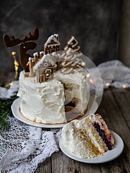 Christmas cake with gingerbread decorations - cookies in shape of homes and snowy trees, moose. Piece of cake. Christmas