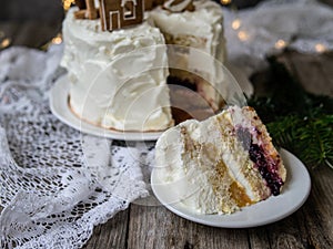 Christmas cake with gingerbread decorations - cookies in shape of homes and snowy trees, moose. Piece of cake. Christmas