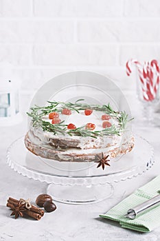 Christmas cake on glass stand decorated with rosemary dried berries