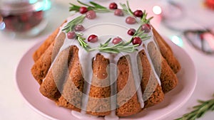 Christmas cake topped with sugar icing, cranberry and rosemary