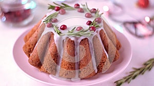 Christmas cake topped with sugar icing, cranberry and rosemary