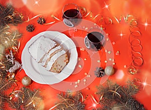 Christmas cake , two glasses of red wine, scattered candied fruits, fir branches and christmas decorations.