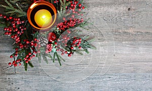 Christmas Candle with Evergreen Tree Branches and Berries Over Rustic Wood