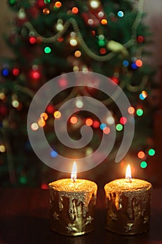 Christmas candle in front of a Christmas tree with sparkling lights and copy space.