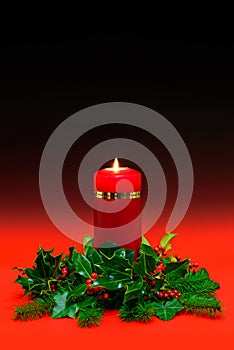 Christmas candle with holly and ivy on red background.