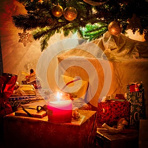 Christmas candle with illuminated fir tree and gifts at house