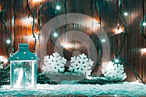 Christmas candle lantern and Christmas tree branches, snow, snowflake and decorations on bokeh background blurred lights