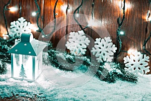 Christmas candle lantern and Christmas tree branches, snow, snowflake and decorations on bokeh background blurred lig