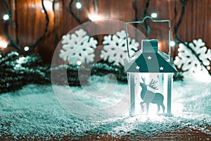 Christmas candle lantern and Christmas tree branches, snow, snowflake and decorations on bokeh background blurred lig