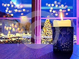 Christmas candle light in blue cup on wooden  window top restaurant interiors  window night city light  reflection blurred ,Tallin