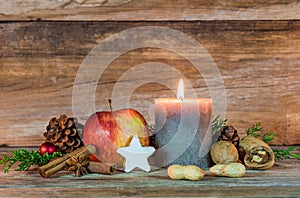 Christmas candle with star cookie, red apple, nuts and spices