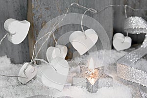 Christmas candle in white with hearts, wood and snow for decoration