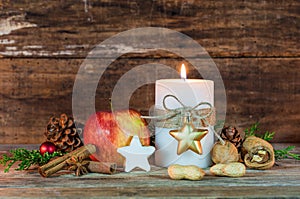 Christmas candle with star cookie, red apple, nuts and spices