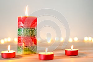 Christmas candles and tealights on wooden table with defocused holiday lights in background