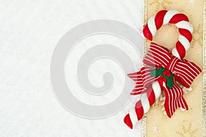 Christmas candy cane with a bow with a gold ribbon on white chevron textured fabric background