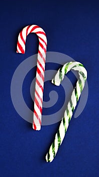 Christmas candy cane. On classic blue background. Flat lay. Vertical mobile format for smartpone stories.