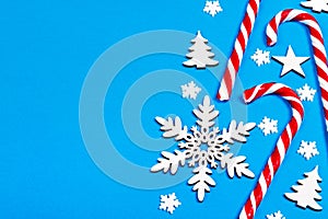 Christmas candy cane lied evenly in row on blue background with decorative snowflake and star. Flat lay and top view