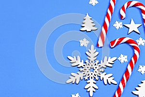 Christmas candy cane lied evenly in row on blue background with decorative snowflake and star. Flat lay and top view