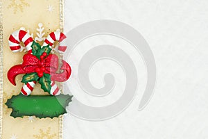 Christmas candy canes with a bow with a gold ribbon on white chevron textured fabric background