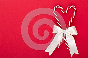 Christmas candy canes, stick and decor on color background. Christmas candy cane heart on an red background