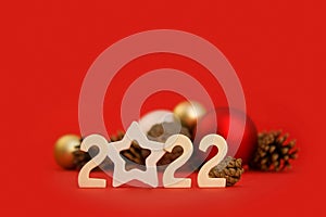 Christmas card with 2022 numbers, new year balls, fir cones on a red background. The basis for a festive layout. Side view.