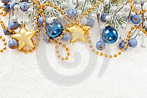 Christmas card border. Xmas composition with green fir branch, gold stars, blue baubles and berries on white snow background