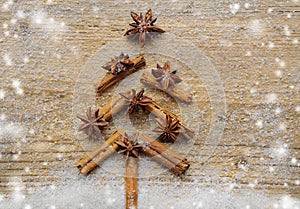 Christmas card with Christmas fir tree made from spices cinnamon sticks, anise star and cane sugar on rustic wooden background