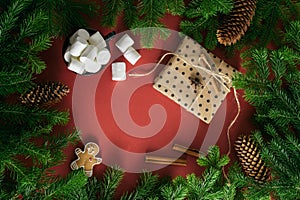 Christmas card. Composition from Christmas decorations, marshmallows, postcard and branches of fir on a red background
