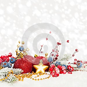 Christmas card composition. Evergreen Xmas tree twig, red holly berries, red baubles on white snow background