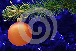Christmas card concept. Orange Christmas bauble and spruce branch with copy space.