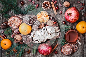 Christmas card. Cookies Chocolate, tea, pomegranate, Tangerines, Nuts, cocoa beans, Fir branches on wooden background.