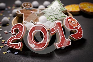 Christmas card on dark background gingerbread red numbers 2019 with slices of orange, multi-colored stars and gingerbread Man