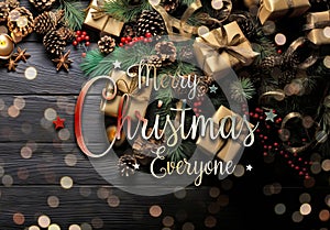 Christmas card with decorations, gifts, pine cones on dark wooden background. Merry Xmas wishes. Happy New Year greetings.