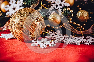 Christmas card with fir tree branch decorated with golden baubles, garlands and vintage snowflakes on a red background.