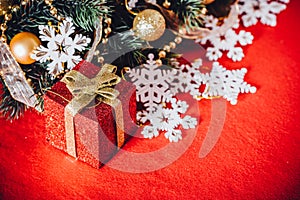 Christmas card with fir tree branch decorated with golden baubles, garlands and vintage snowflakes on a red background.