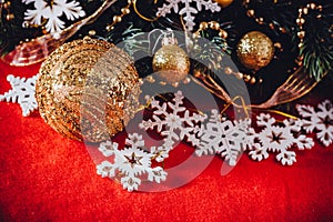 Christmas card with fir tree branch decorated with golden baubles, garlands and vintage snowflakes on a red background.