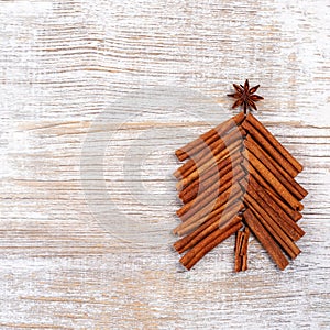 Christmas card with fir tree made from spices cinnamon sticks, anise star on rustic wooden background. Celebration concept. Place
