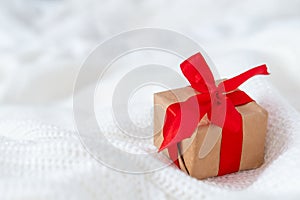 Christmas card with gift box red ribbon on white knitted sweater background. Copyspace