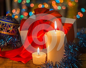 Christmas card with gift and candles on bokeh background