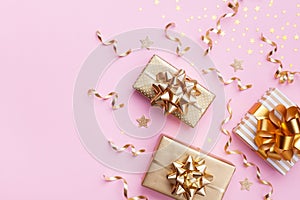 Christmas card. Golden gift or present boxes and star confetti on pink background top view. Flat lay